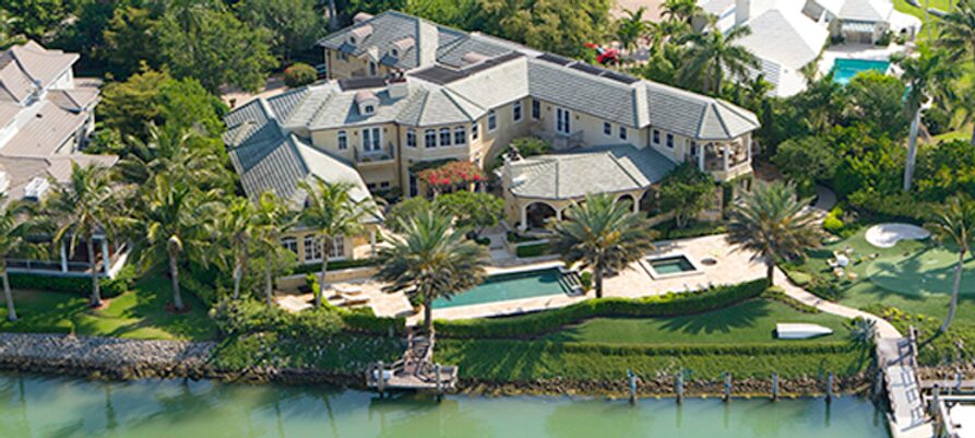 A large house with a pool and palm trees.