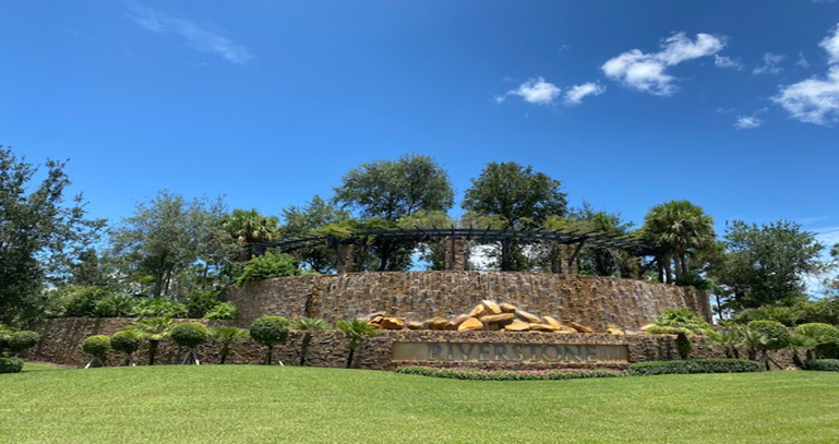 A stone wall with trees and bushes in the background.