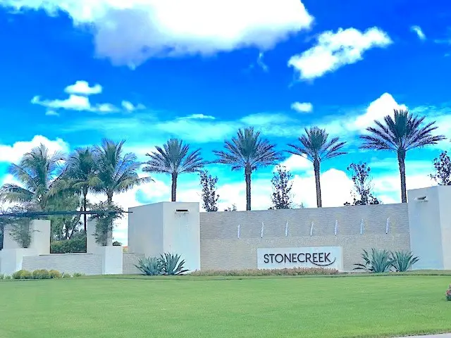 A sign that says stonecreek in front of palm trees.