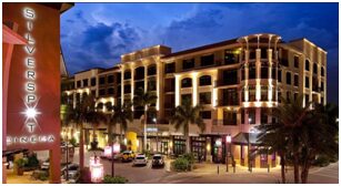 A hotel with palm trees and lights at night.