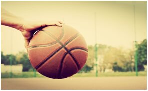 A person holding onto a basketball on the court