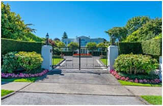 A gated driveway with flowers around it.