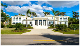 A large white house with palm trees in front of it.