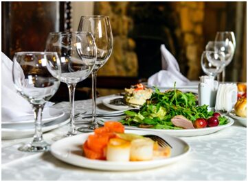 A table with plates of food and wine glasses.