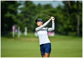 A woman is swinging at the golf course