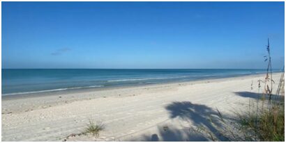 A beach with white sand and blue water.