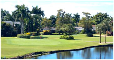 A golf course with trees and water in the background.