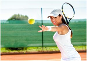 A woman swinging at a tennis ball with her racket.