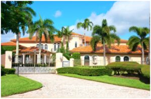 A large house with palm trees and bushes.