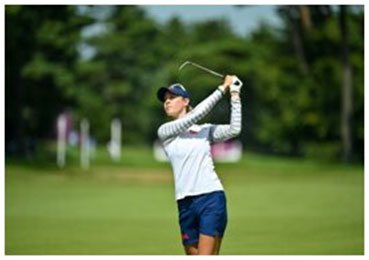 A woman is swinging at the golf course