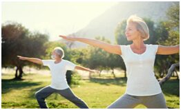 Two people doing yoga in a park.