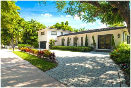 A large driveway with a house and trees in the background.