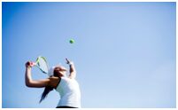 A woman swinging at a tennis ball with her racket.