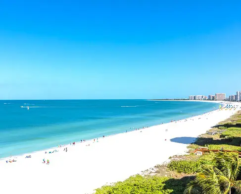 A beach with people walking on it and the ocean in the background.